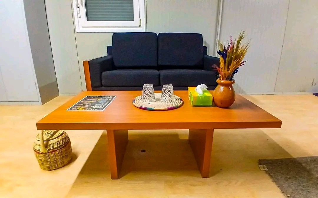 Table basse dressée avec verres et vase de fleurs séchées devant un canapé
